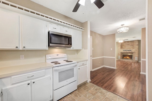1002 Williams St, Cleveland, TX 77327 - kitchen with stainless steel microwave, white electric range, ceiling fan, white cabinetry, and light countertops
