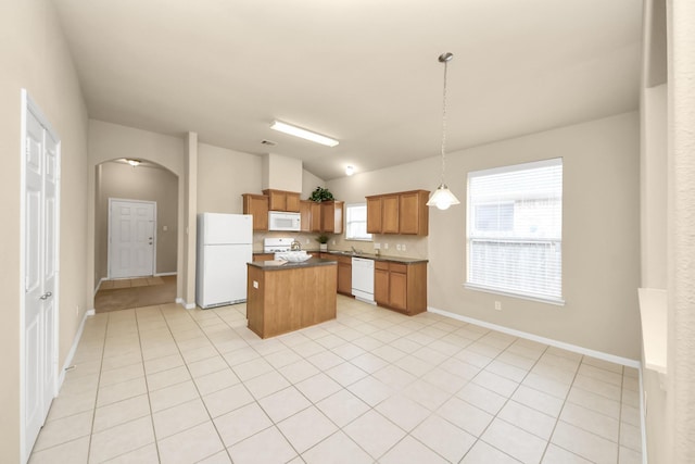20234 Goss Hollow Ln, Katy, TX 77449 - kitchen featuring white appliances, arched walkways, dark countertops, a kitchen island, and vaulted ceiling