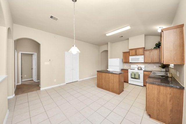 20234 Goss Hollow Ln, Katy, TX 77449 - kitchen featuring white appliances, arched walkways, a center island, decorative backsplash, and light tile patterned floors