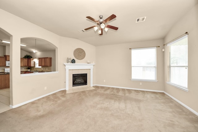 20234 Goss Hollow Ln, Katy, TX 77449 - unfurnished living room with ceiling fan, light carpet, arched walkways, a tiled fireplace, and lofted ceiling