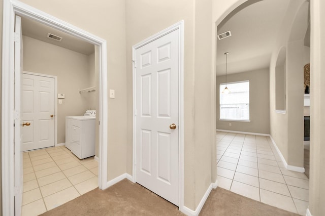 20234 Goss Hollow Ln, Katy, TX 77449 - washroom featuring arched walkways, washing machine and clothes dryer, light tile patterned floors, and light carpet