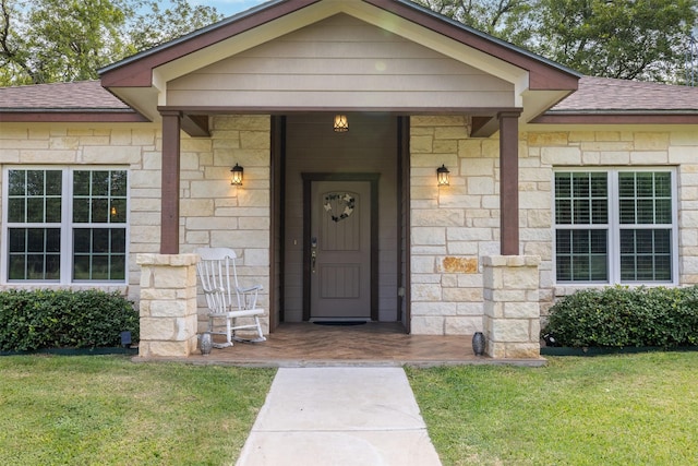 194 2 Mile Ln, Smithville, TX 78957 - view of exterior entry featuring a shingled roof, stone siding, and a lawn