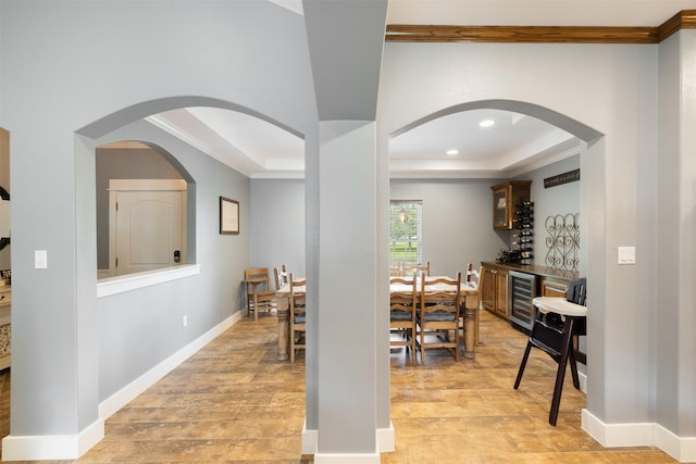 194 2 Mile Ln, Smithville, TX 78957 - dining space with beverage cooler, a raised ceiling, light wood finished floors, ornamental molding, and arched walkways