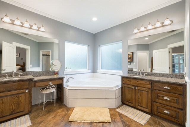 194 2 Mile Ln, Smithville, TX 78957 - bathroom with plenty of natural light, a garden tub, two vanities, wood finished floors, and ornamental molding