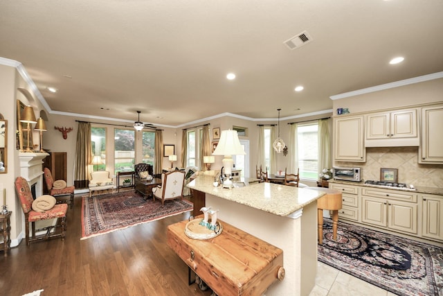 9419 Pecos Pass Ct, Cypress, TX 77433 - kitchen featuring cream cabinetry, stainless steel gas cooktop, recessed lighting, light stone countertops, and crown molding