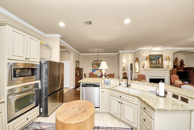 9419 Pecos Pass Ct, Cypress, TX 77433 - kitchen with appliances with stainless steel finishes, arched walkways, a fireplace, a large island with sink, and light stone countertops