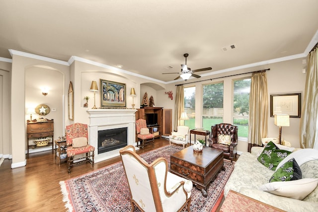 9419 Pecos Pass Ct, Cypress, TX 77433 - living room with wood finished floors, a glass covered fireplace, crown molding, a ceiling fan, and arched walkways