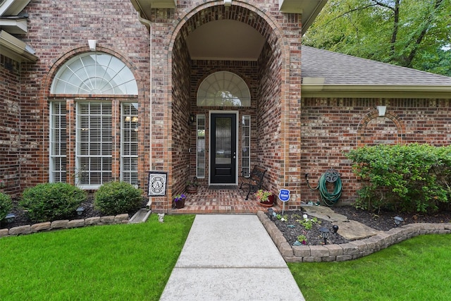 3330 Lake Island Dr, Montgomery, TX 77356 - view of exterior entry with brick siding, roof with shingles, and a yard