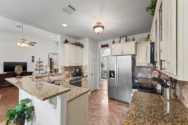 3330 Lake Island Dr, Montgomery, TX 77356 - kitchen featuring appliances with stainless steel finishes, a peninsula, backsplash, light stone counters, and a kitchen breakfast bar