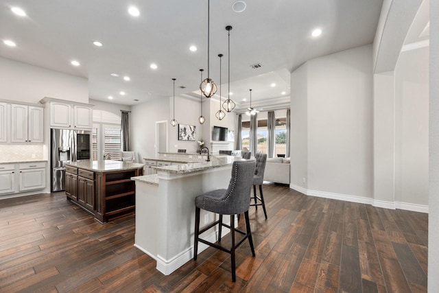 19219 Spotted Bass Ln, Cypress, TX 77433 - kitchen featuring stainless steel refrigerator with ice dispenser, a spacious island, dark wood-type flooring, a breakfast bar area, and recessed lighting