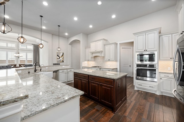 19219 Spotted Bass Ln, Cypress, TX 77433 - kitchen featuring appliances with stainless steel finishes, a large island with sink, arched walkways, tasteful backsplash, and recessed lighting