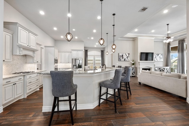 19219 Spotted Bass Ln, Cypress, TX 77433 - kitchen featuring stainless steel appliances, open floor plan, backsplash, a ceiling fan, and a kitchen bar