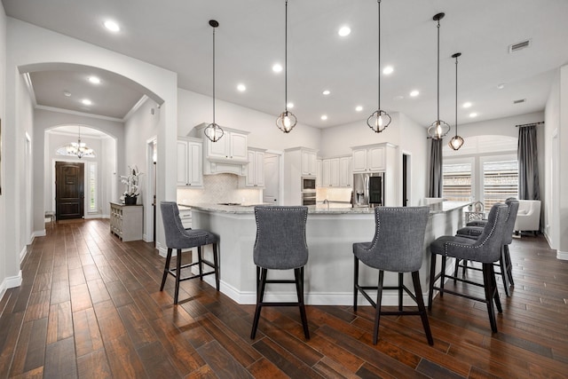 19219 Spotted Bass Ln, Cypress, TX 77433 - kitchen with arched walkways, stainless steel appliances, a kitchen breakfast bar, dark wood-type flooring, and recessed lighting