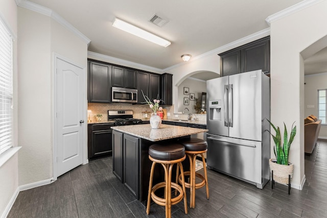 4663 Trembling Forest Ln, Houston, TX 77092 - kitchen featuring appliances with stainless steel finishes, arched walkways, a center island, decorative backsplash, and dark wood finished floors