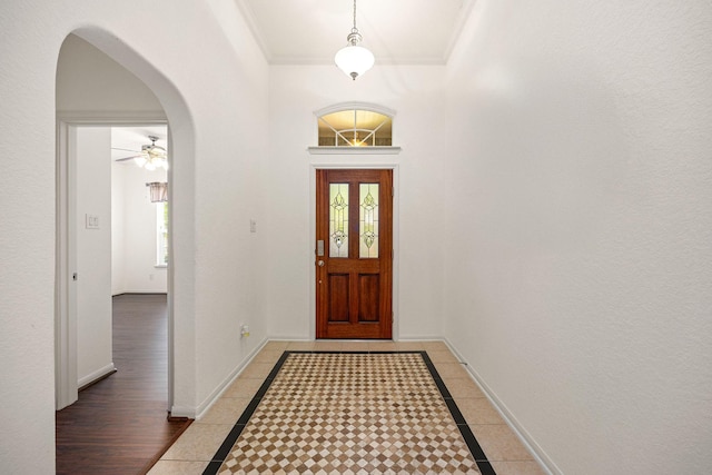 6230 Ledger Ln, Missouri City, TX 77459 - foyer featuring arched walkways, inlaid floor details, a ceiling fan, and ornamental molding