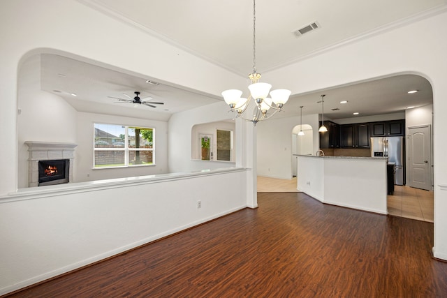 6230 Ledger Ln, Missouri City, TX 77459 - unfurnished living room featuring wood finished floors, arched walkways, a tiled fireplace, a chandelier, and recessed lighting