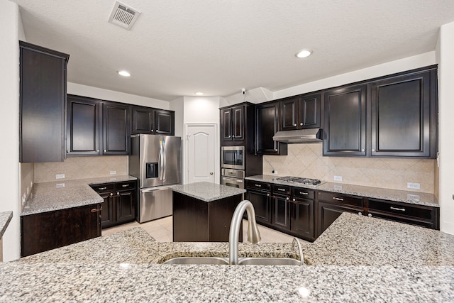 6230 Ledger Ln, Missouri City, TX 77459 - kitchen with appliances with stainless steel finishes, light stone countertops, decorative backsplash, recessed lighting, and a center island