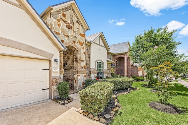 6230 Ledger Ln, Missouri City, TX 77459 - view of front of home with stone siding, a front lawn, stucco siding, an attached garage, and driveway