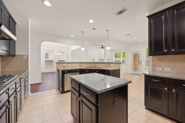 6230 Ledger Ln, Missouri City, TX 77459 - kitchen with appliances with stainless steel finishes, a kitchen island, tasteful backsplash, a ceiling fan, and light tile patterned floors
