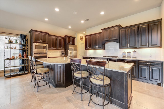 3411 Brampton Island Dr, Katy, TX 77494 - kitchen featuring appliances with stainless steel finishes, a breakfast bar area, a large island, decorative backsplash, and light stone counters