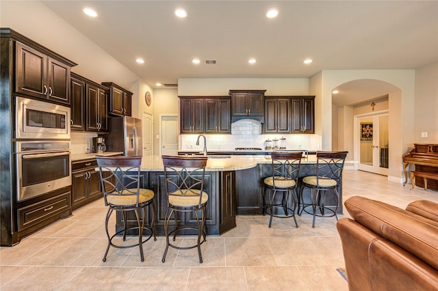 3411 Brampton Island Dr, Katy, TX 77494 - kitchen with appliances with stainless steel finishes, backsplash, arched walkways, a kitchen bar, and recessed lighting
