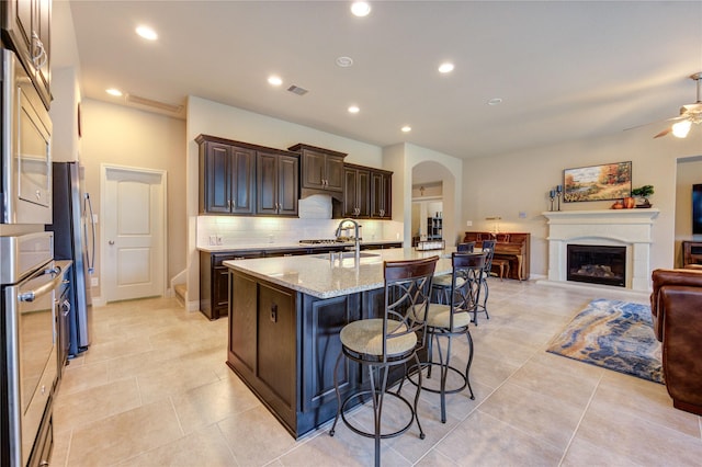 3411 Brampton Island Dr, Katy, TX 77494 - kitchen with arched walkways, open floor plan, stainless steel appliances, a ceiling fan, and a breakfast bar area