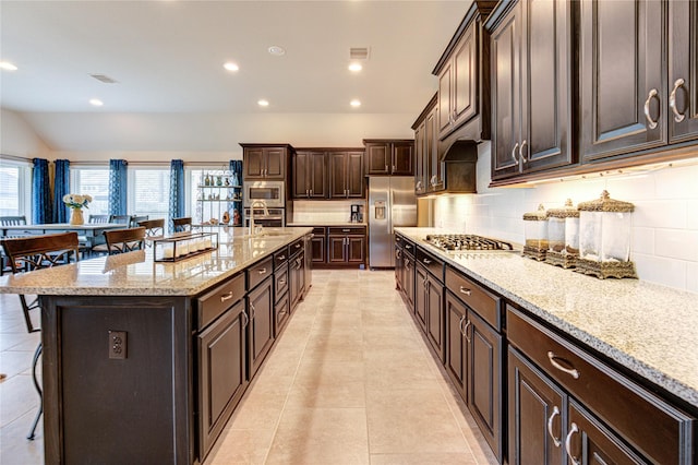 3411 Brampton Island Dr, Katy, TX 77494 - kitchen featuring appliances with stainless steel finishes, a kitchen breakfast bar, tasteful backsplash, recessed lighting, and light stone countertops