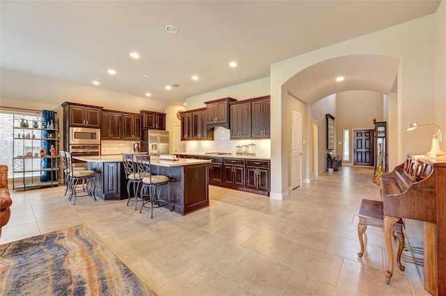 3411 Brampton Island Dr, Katy, TX 77494 - kitchen with appliances with stainless steel finishes, a breakfast bar, decorative backsplash, light countertops, and arched walkways