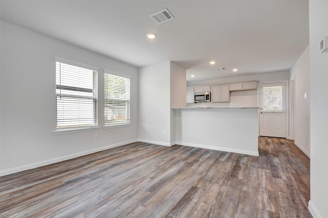 1316 Farquhar St, Navasota, TX 77868 - kitchen with stainless steel microwave, plenty of natural light, wood finished floors, recessed lighting, and light countertops