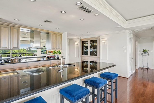 49 Briar Hollow Ln Unit 702, Houston, TX 77027 - kitchen with island exhaust hood, recessed lighting, ornamental molding, a kitchen breakfast bar, and dark wood finished floors
