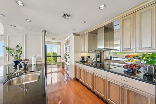 49 Briar Hollow Ln Unit 702, Houston, TX 77027 - kitchen featuring wall chimney range hood, appliances with stainless steel finishes, light wood-style flooring, recessed lighting, and dark stone countertops