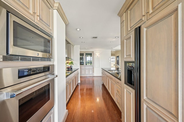 49 Briar Hollow Ln Unit 702, Houston, TX 77027 - kitchen featuring stainless steel appliances, wood finished floors, recessed lighting, crown molding, and dark countertops
