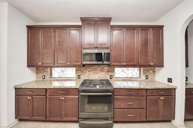 6423 Middlelake Ct, Katy, TX 77450 - kitchen featuring appliances with stainless steel finishes, arched walkways, backsplash, and light stone countertops