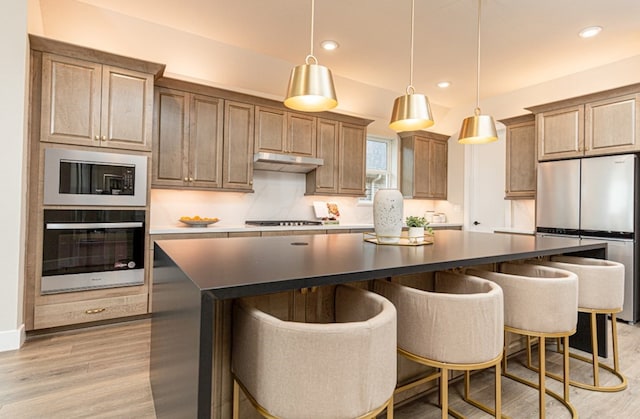 19207 Seabiscuit Stable Trl, Tomball, TX 77377 - kitchen featuring stainless steel appliances, under cabinet range hood, a kitchen island, light wood-style flooring, and dark countertops