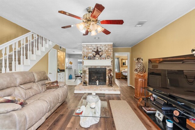 19511 Oak Station Dr, Humble, TX 77346 - living area with stairs, ceiling fan, wood finished floors, a fireplace, and ornamental molding