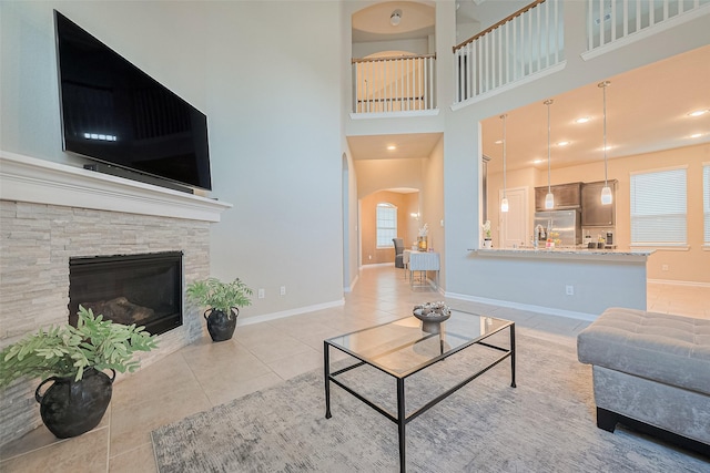 2526 Granberry Pt, Missouri City, TX 77459 - tiled living room featuring arched walkways, a stone fireplace, and a towering ceiling