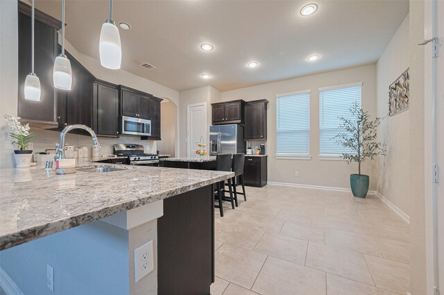 2526 Granberry Pt, Missouri City, TX 77459 - kitchen with stainless steel appliances, recessed lighting, decorative light fixtures, light tile patterned floors, and light stone countertops