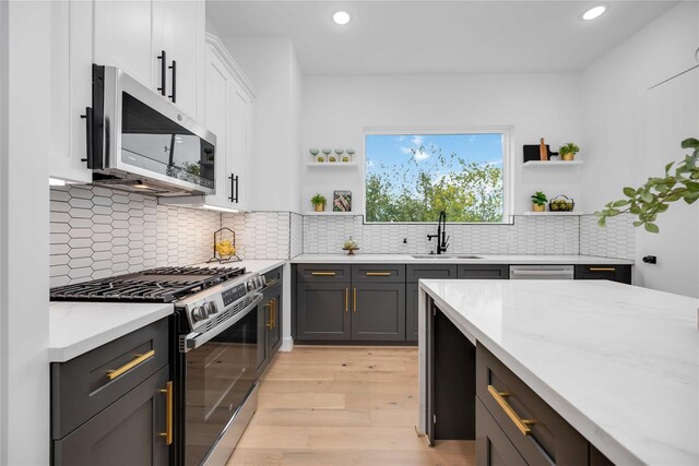 2506 Tierwester St, Houston, TX 77004 - kitchen with stainless steel appliances, open shelves, light wood-type flooring, recessed lighting, and white cabinetry