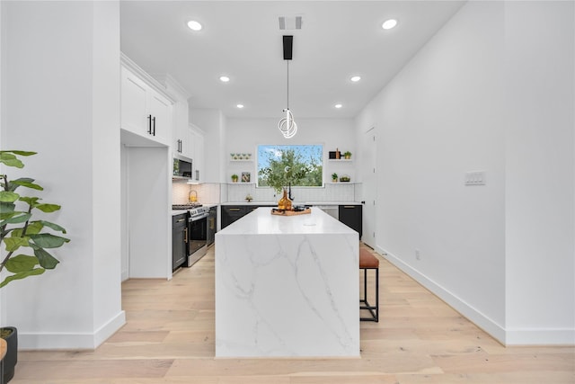 2506 Tierwester St, Houston, TX 77004 - kitchen with stainless steel appliances, open shelves, a kitchen island, backsplash, and white cabinetry