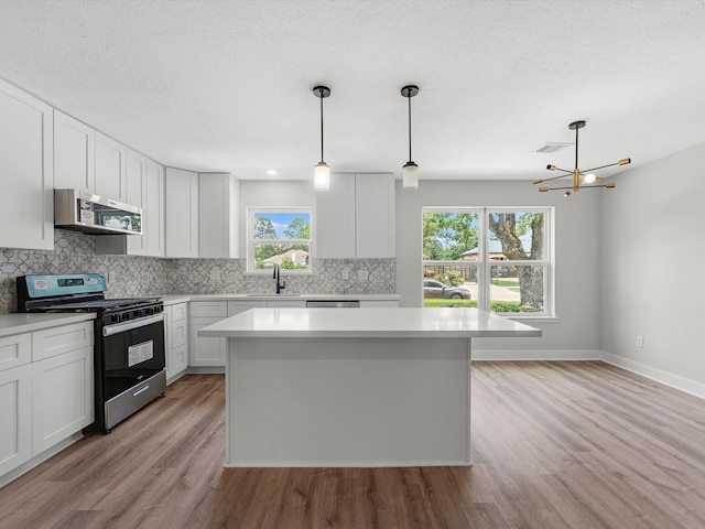 2515 Garapan St, Houston, TX 77091 - kitchen featuring stainless steel appliances, tasteful backsplash, light countertops, light wood-style flooring, and a center island