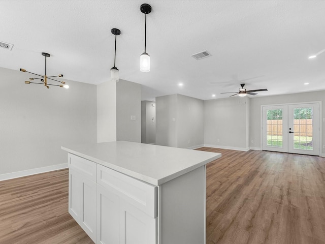 2515 Garapan St, Houston, TX 77091 - kitchen featuring white cabinetry, light wood-type flooring, a kitchen island, a chandelier, and light countertops