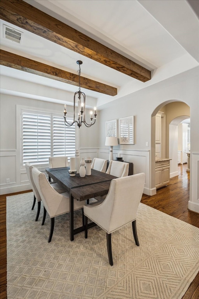 3310 Glen Haven Blvd, Houston, TX 77025 - dining space with a decorative wall, arched walkways, wood finished floors, a chandelier, and beamed ceiling