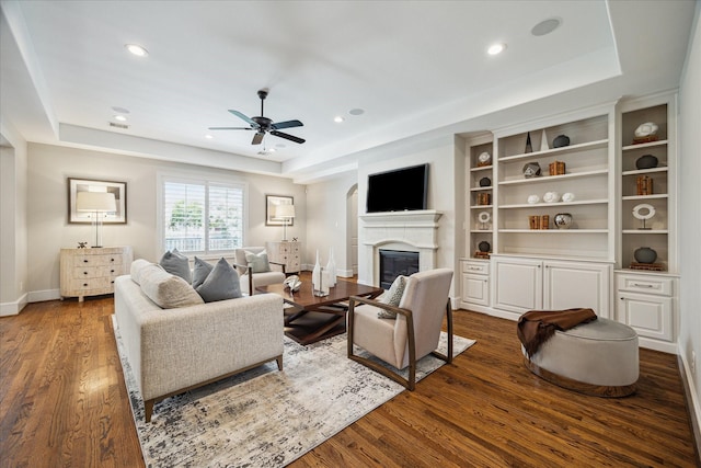 3310 Glen Haven Blvd, Houston, TX 77025 - living room featuring a raised ceiling, a glass covered fireplace, a ceiling fan, wood finished floors, and recessed lighting