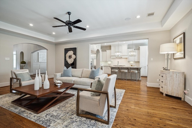 3310 Glen Haven Blvd, Houston, TX 77025 - living area featuring arched walkways, wood finished floors, ceiling fan, recessed lighting, and a tray ceiling