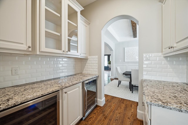 3310 Glen Haven Blvd, Houston, TX 77025 - kitchen with beverage cooler, arched walkways, dark wood-style flooring, light stone counters, and a wainscoted wall