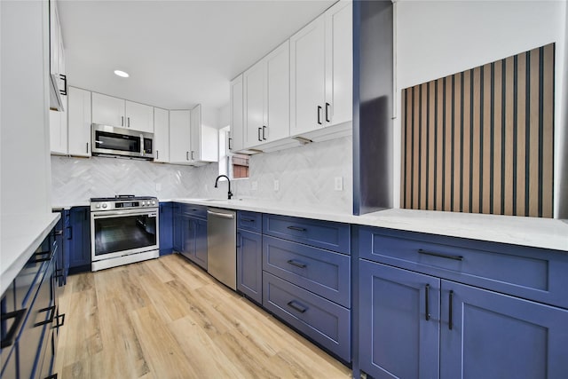 9622 Clanton St, Houston, TX 77080 - kitchen featuring appliances with stainless steel finishes, blue cabinets, light wood-style floors, white cabinetry, and recessed lighting