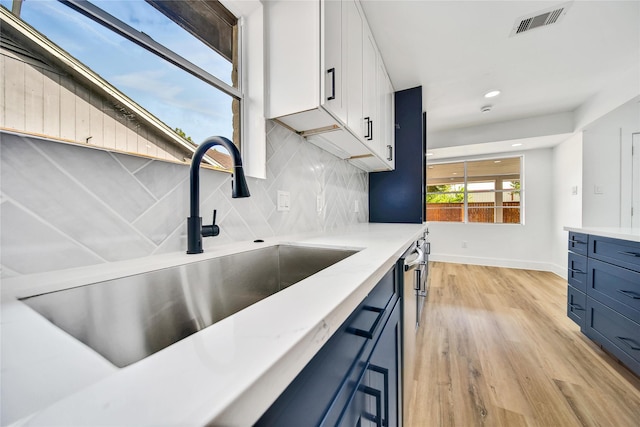 9622 Clanton St, Houston, TX 77080 - kitchen featuring blue cabinetry, tasteful backsplash, light wood-style flooring, recessed lighting, and white cabinetry