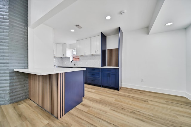 9622 Clanton St, Houston, TX 77080 - kitchen with a peninsula, blue cabinetry, white cabinetry, light countertops, and decorative backsplash