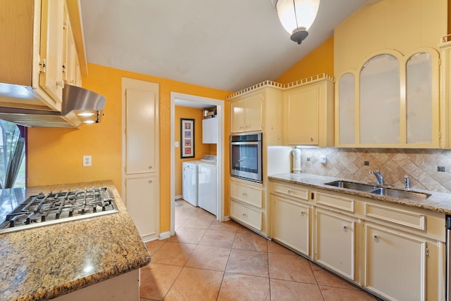 2902 Rainwood St, Spring, TX 77388 - kitchen with washer and dryer, stainless steel appliances, cream cabinets, backsplash, and lofted ceiling
