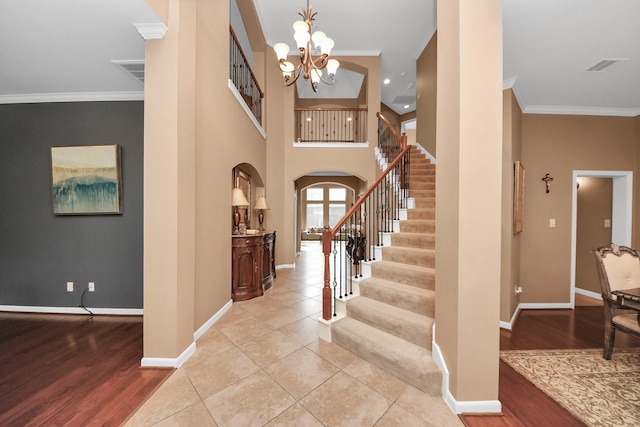 13723 Playa Lucia Ct, Houston, TX 77044 - foyer entrance featuring arched walkways, a chandelier, stairs, crown molding, and light wood-type flooring
